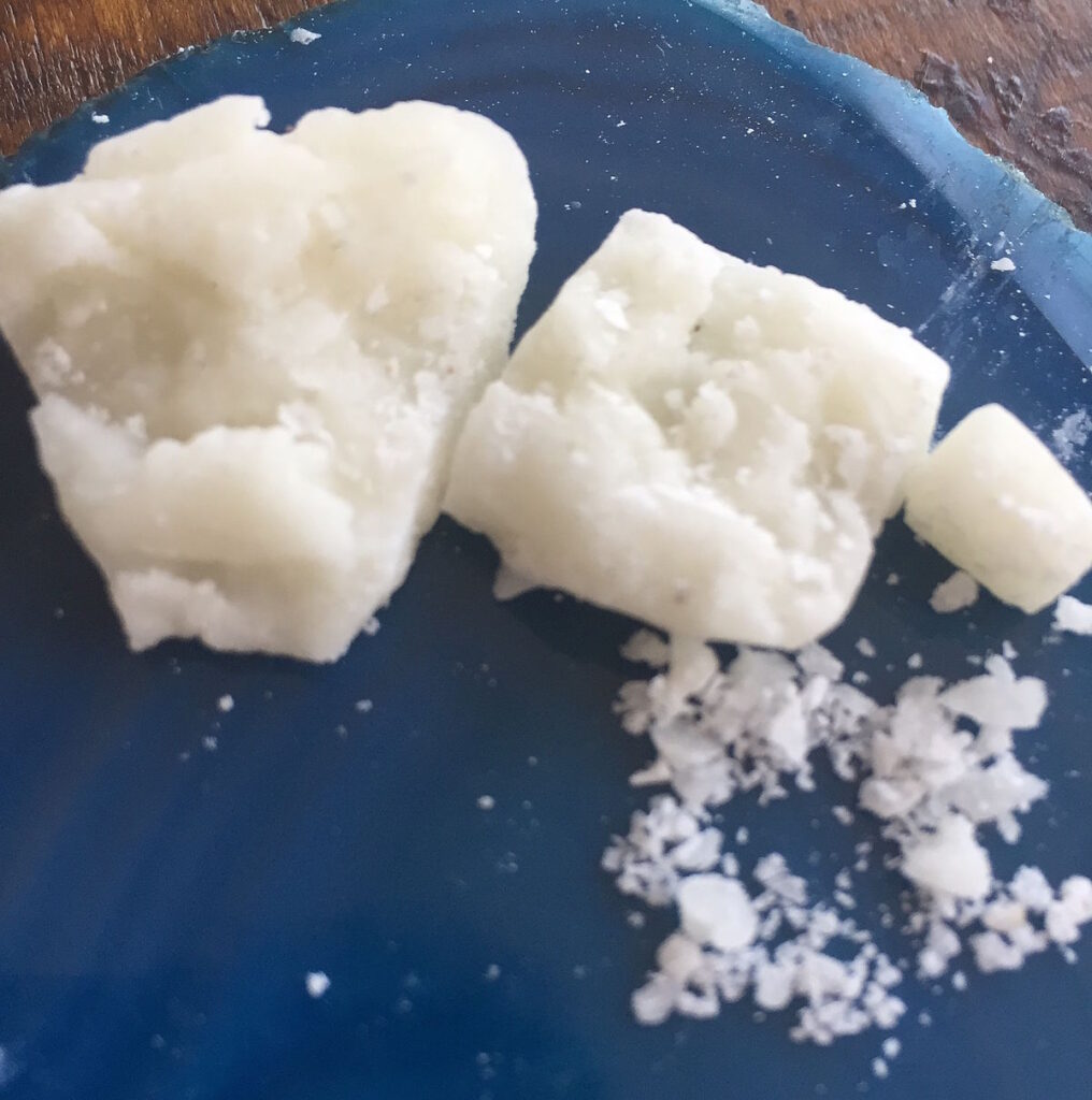 Close-up of a small quantity of crack-cocaine sitting on a blue plate on a table.